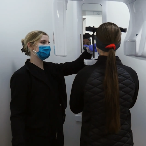 Photo of a dental assistant setting some one up to take an X-ray