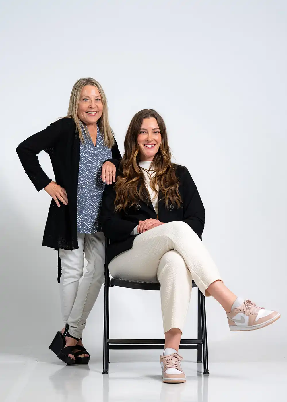 Photo of two dental instructors, Ashley sitting on a chair, and Tammy standing next to Ashley.