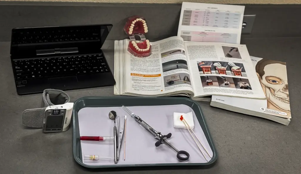 Photo of dental equipment and books on a table, dentiform, omron sensor, and an open laptop